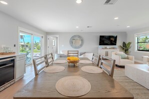 A modern kitchen with a dining area, a television, and a view of the outdoors. - 🏖️Private Heated Pool | Canal Front | Gorgeous Views | Barefoot Escape🏖️ (Fort Myers Beach)