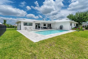 A modern house with a swimming pool, a covered patio, and a lawn. - 🏖️Private Heated Pool | Canal Front | Gorgeous Views | Barefoot Escape🏖️ (Fort Myers Beach)