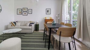 A modern living room with a sofa, a dining table with chairs, a coffee table, and a fireplace. - Charmante maison 6PAX proche Arc de Triomphe (Paris)