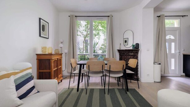 A living room with a sofa, dining table, chairs, a cabinet, and a fireplace. - Charmante maison 6PAX proche Arc de Triomphe (Paris)