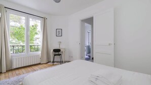 A bedroom with a bed, a desk, a chair, and a window with curtains. - Charmante maison 6PAX proche Arc de Triomphe (Paris)