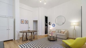 A modern living room with a dining table, a sofa, a yellow chair, and a patterned rug. - Perretti - Spacious Flat 2BDR Paris Neuilly (Neuilly-sur-Seine)