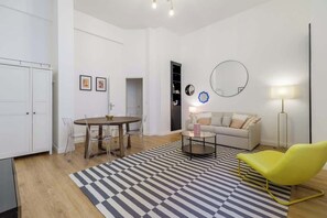 A modern living room with a dining table, a sofa, a yellow chair, and a patterned rug. - Perretti - Spacious Flat 2BDR Paris Neuilly (Neuilly-sur-Seine)