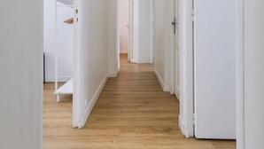 A long, narrow hallway with white walls and wooden flooring, leading to multiple doors. - Perretti - Spacious Flat 2BDR Paris Neuilly (Neuilly-sur-Seine)