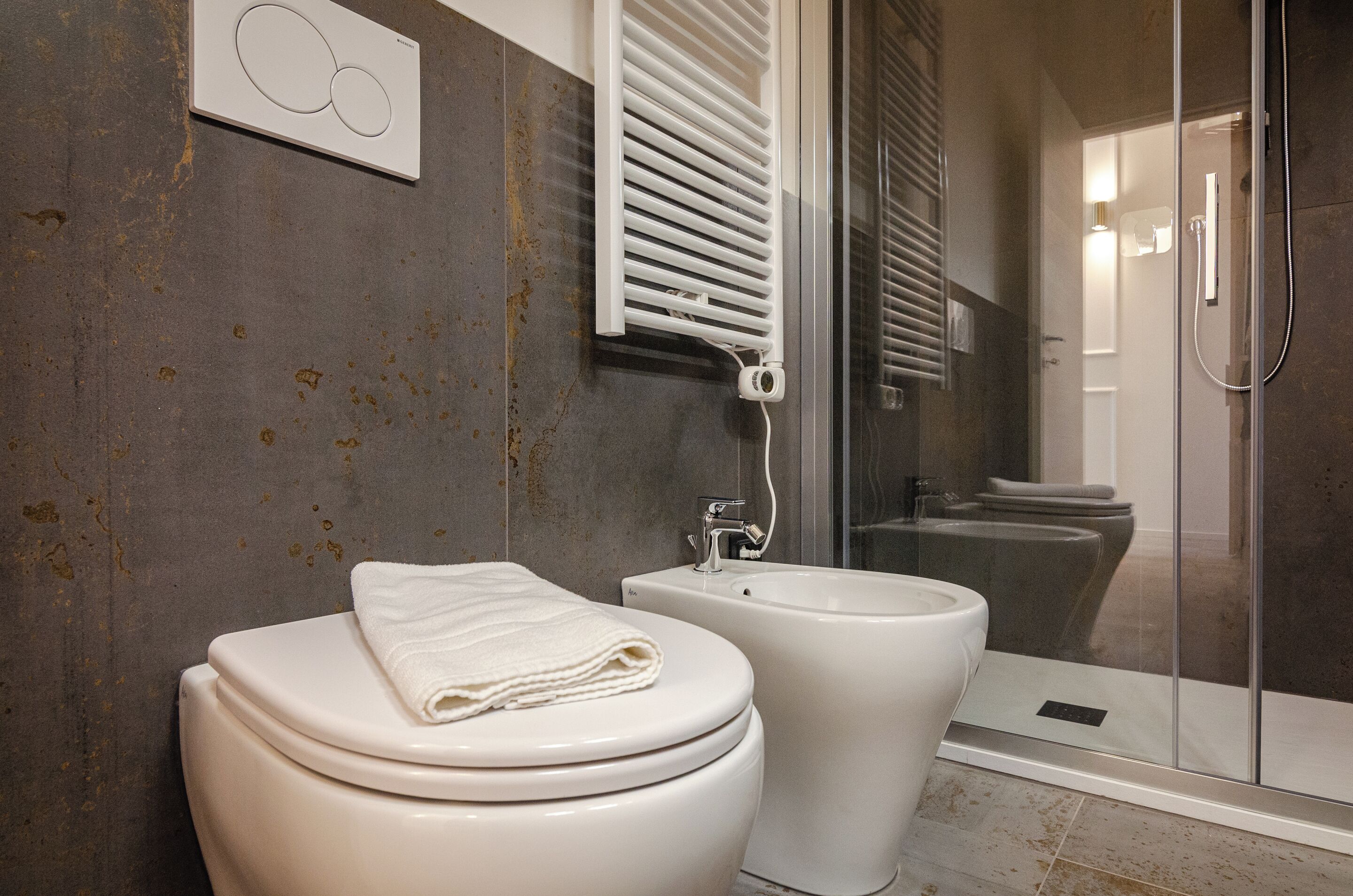 A bathroom with a toilet, bidet, and glass shower enclosure.