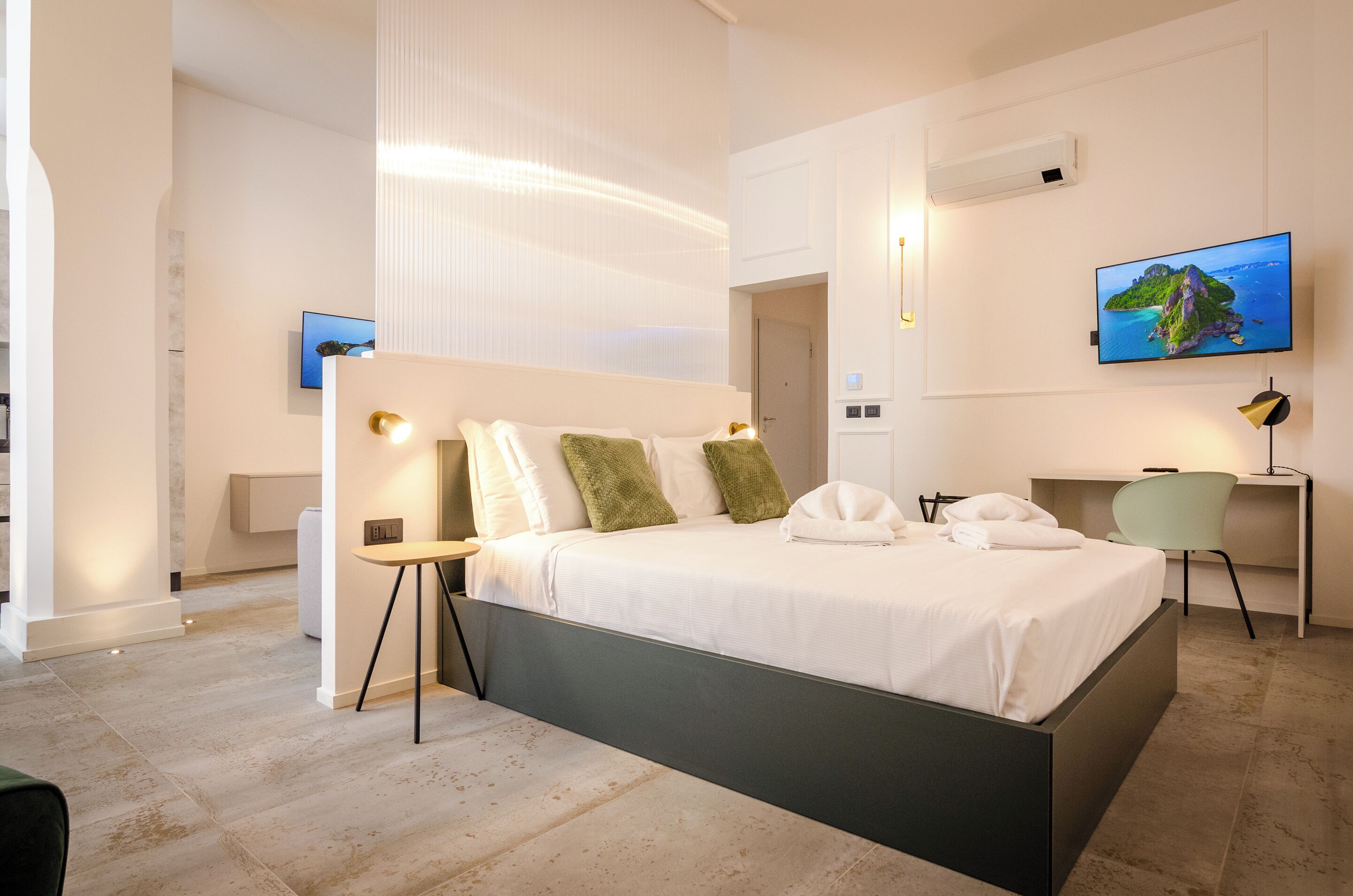 Une chambre d’hôtel moderne équipée d’un grand lit, d’un bureau, d’une chaise, d’une télévision et d’un climatiseur fixé au mur.