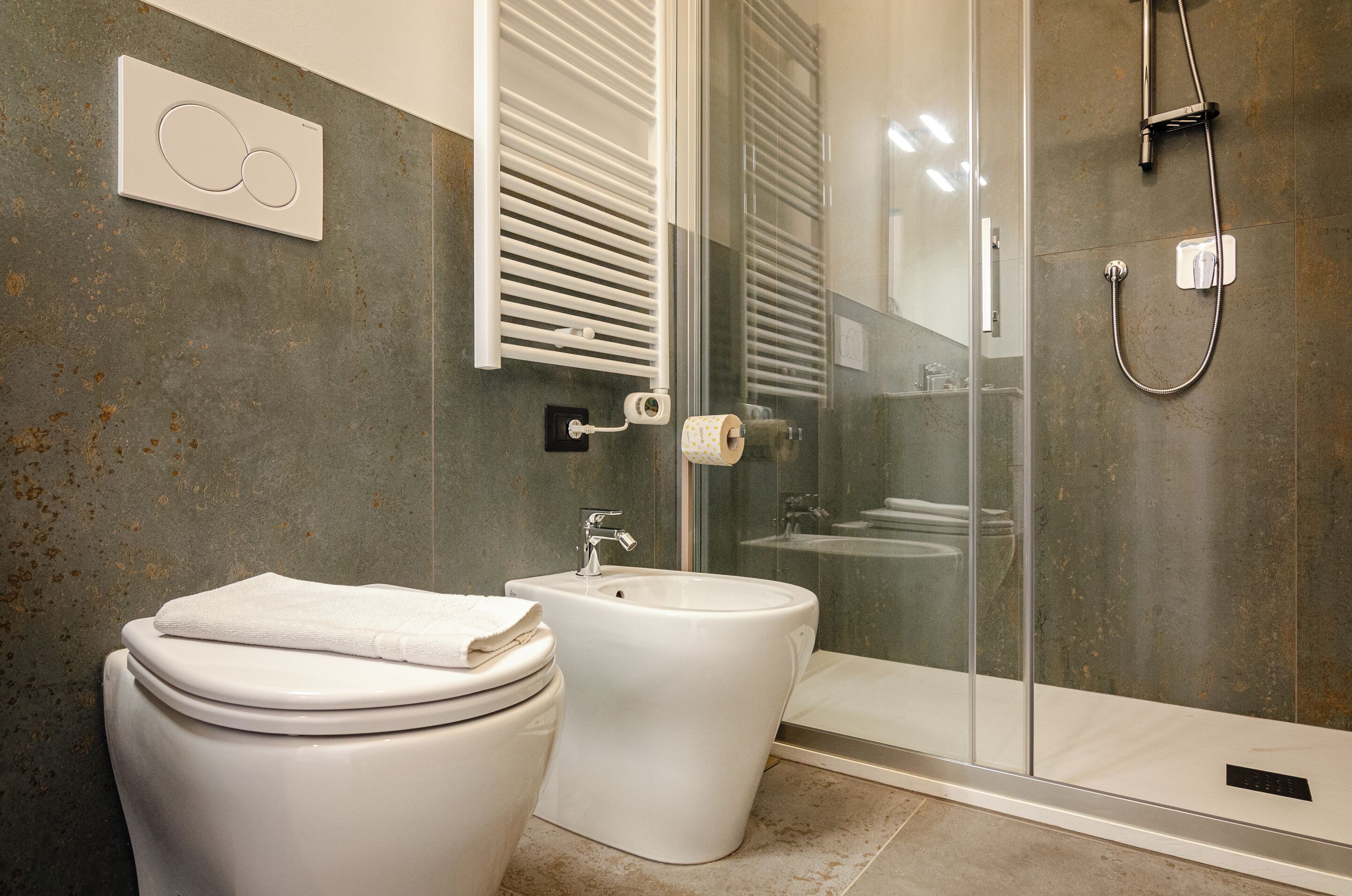 A bathroom with a toilet, bidet, and glass-enclosed shower.