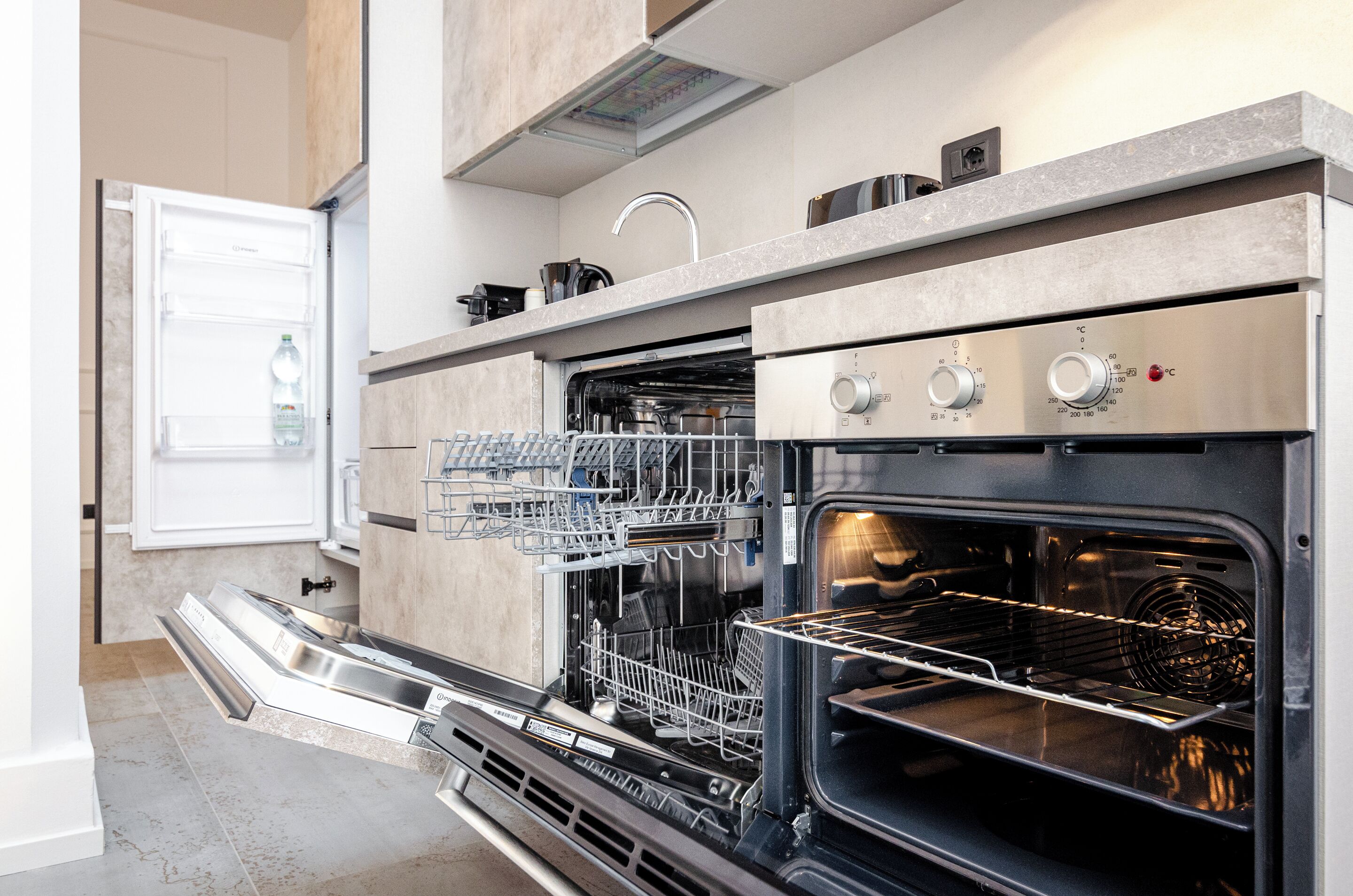 A kitchen with a built-in dishwasher, oven, and a stainless steel range hood.