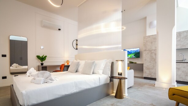 A modern hotel room with a large bed, a TV, a small desk, and a bathroom. - Albani Lofts (Bologna)