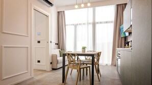A modern dining area with a table and chairs, a sofa, and a TV mounted on the wall. - Albani Lofts (Bologna)