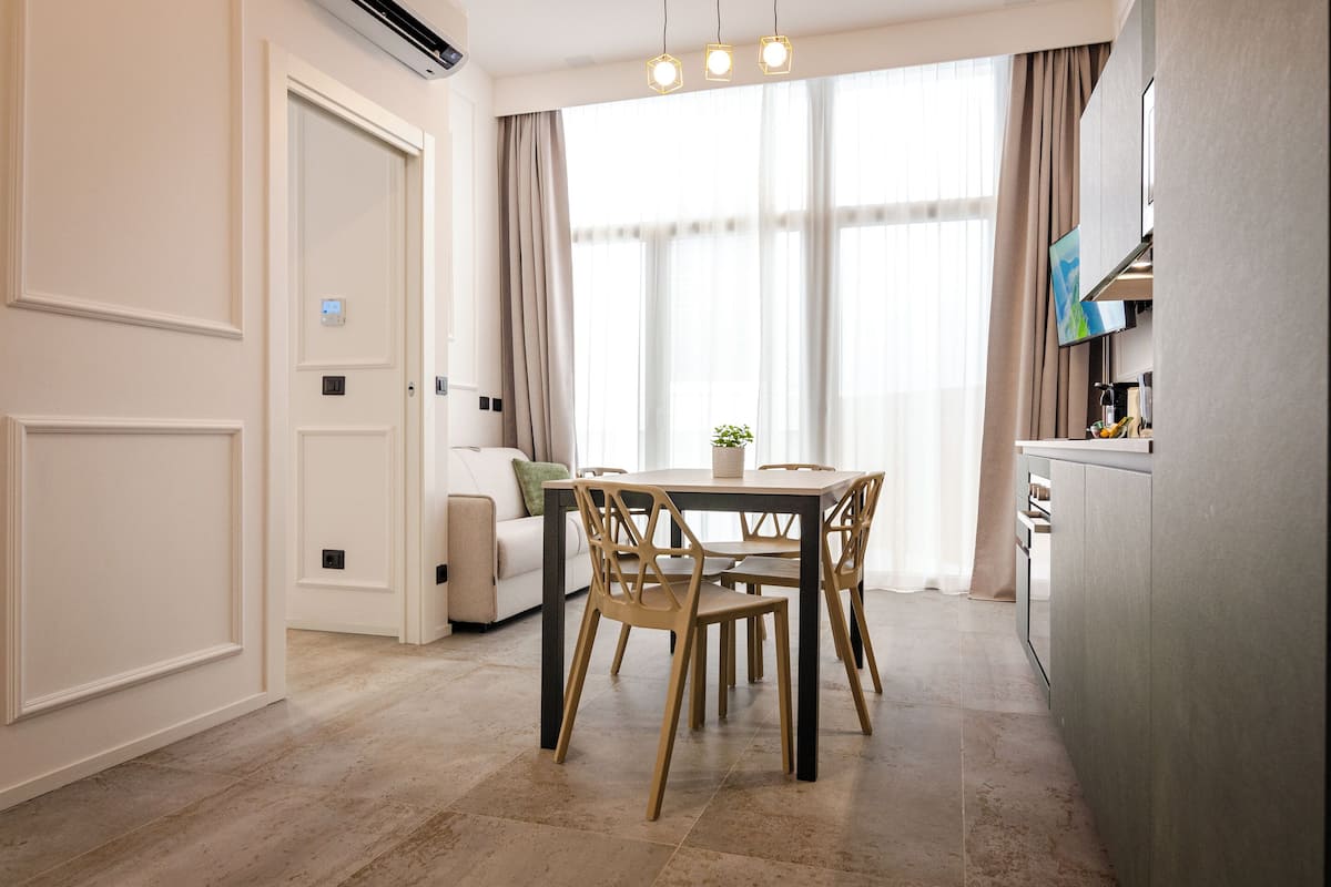 A modern dining area with a table and chairs, a sofa, and a TV mounted on the wall.