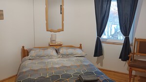 A room with a bed, a bedside table with a lamp, a mirror, a window with curtains, and a chair. - Charming Villa with AC, Barbecue and Pool  in peaceful Kramolin (Kramolin)