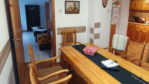 A dining area with a wooden table, chairs, and a black table runner. A calendar and a framed picture are on the wall. - Charming Villa with AC, Barbecue and Pool  in peaceful Kramolin (Kramolin)