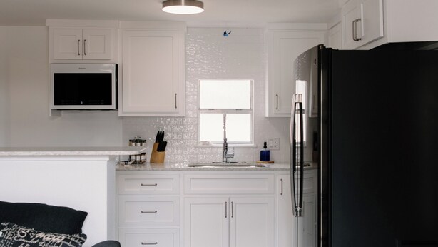 A modern kitchen with white cabinets, a black refrigerator, and a wooden floor. - Urban Chic 1 BR - Downtown Abilene -  Data Center (Abilene)
