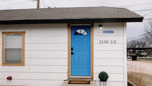 A single-story house with a blue door, a small window with a wooden frame, and a welcome mat at the entrance. - Urban Chic 1 BR - Downtown Abilene -  Data Center (Abilene)