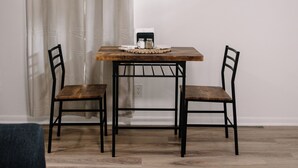 A dining area with a wooden table, two chairs, a framed picture on the wall, and a window with curtains. - Urban Chic 1 BR - Downtown Abilene -  Data Center (Abilene)