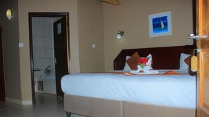 Habitació d'hotel amb un llit, un bany i una porta que dona a una altra habitació.