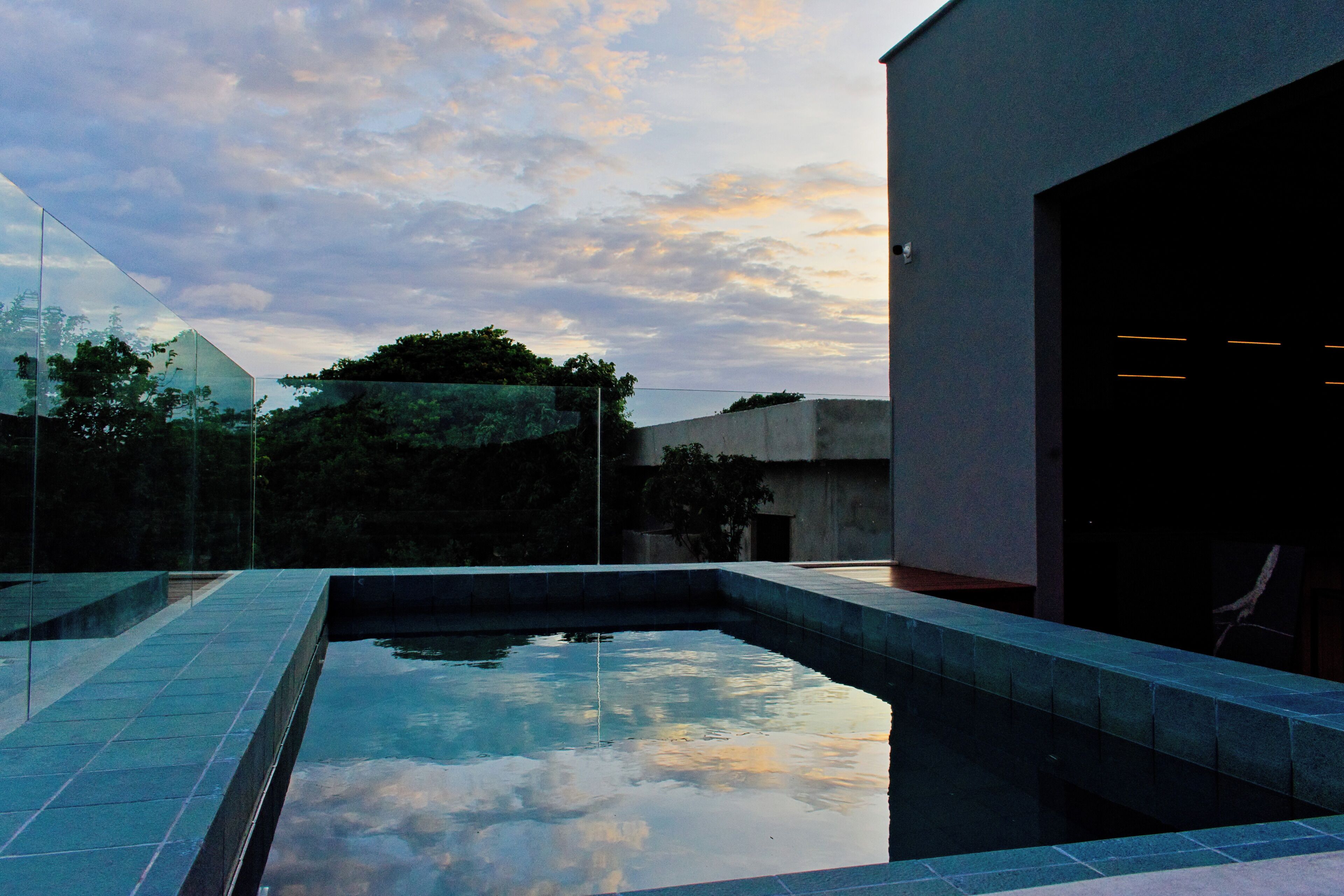 A modern outdoor pool area with a clear sky and a building in the background.