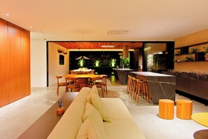 A modern kitchen with a dining area, wooden flooring, and a sofa with cushions. - Luxury Mansion VILLA MARIA (brand new) (Tibau do Sul- RN)