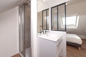 A modern bedroom with a skylight, a white vanity with a mirror, and a bed with a grey headboard. - Holiday Home 'Refuge du Sentier Sauvage' with Private Terrace (Belz)