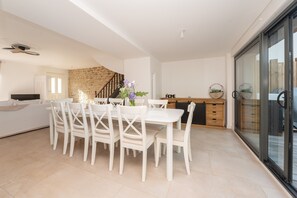 A modern kitchen with a dining area, a staircase, and a sliding glass door leading to a balcony. - Holiday Home 'Refuge du Sentier Sauvage' with Private Terrace (Belz)