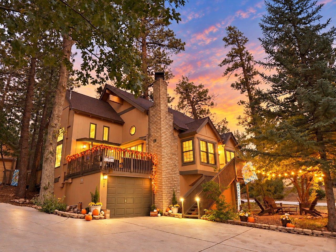 A two-story house with a garage, a balcony with string lights, and a staircase leading to the second floor.