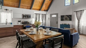 Una cucina moderna con travi in legno, un'area pranzo con tavolo in legno e un divano blu.