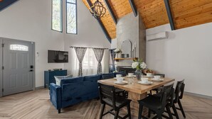 Un interno moderno con zona pranzo, un divano blu, una TV e un camino.