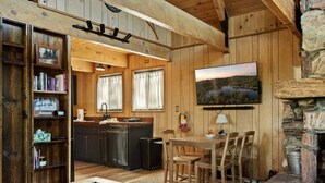 A rustic cabin interior with a wooden dining area, kitchen, and a stone fireplace. - The Silver Coyote, w/ Bear Mtn Views & Firepit (Big Bear Lake)