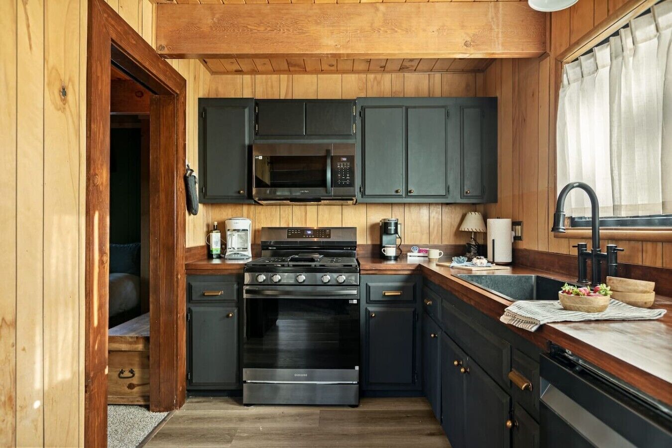 A compact kitchen with a stove, microwave, and dark cabinets.