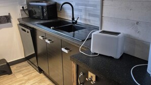 A modern kitchen with a black countertop, stainless steel appliances, and wooden cabinets. - Large T5 for 7 people (Angers)