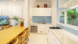 A modern kitchen with a dining area, built-in cabinets, a dishwasher, and a large window with a view. - Modern Luxury 6Br Villa In Canggu - Rooftop - Ricefields - Large Groups (Tabanan)
