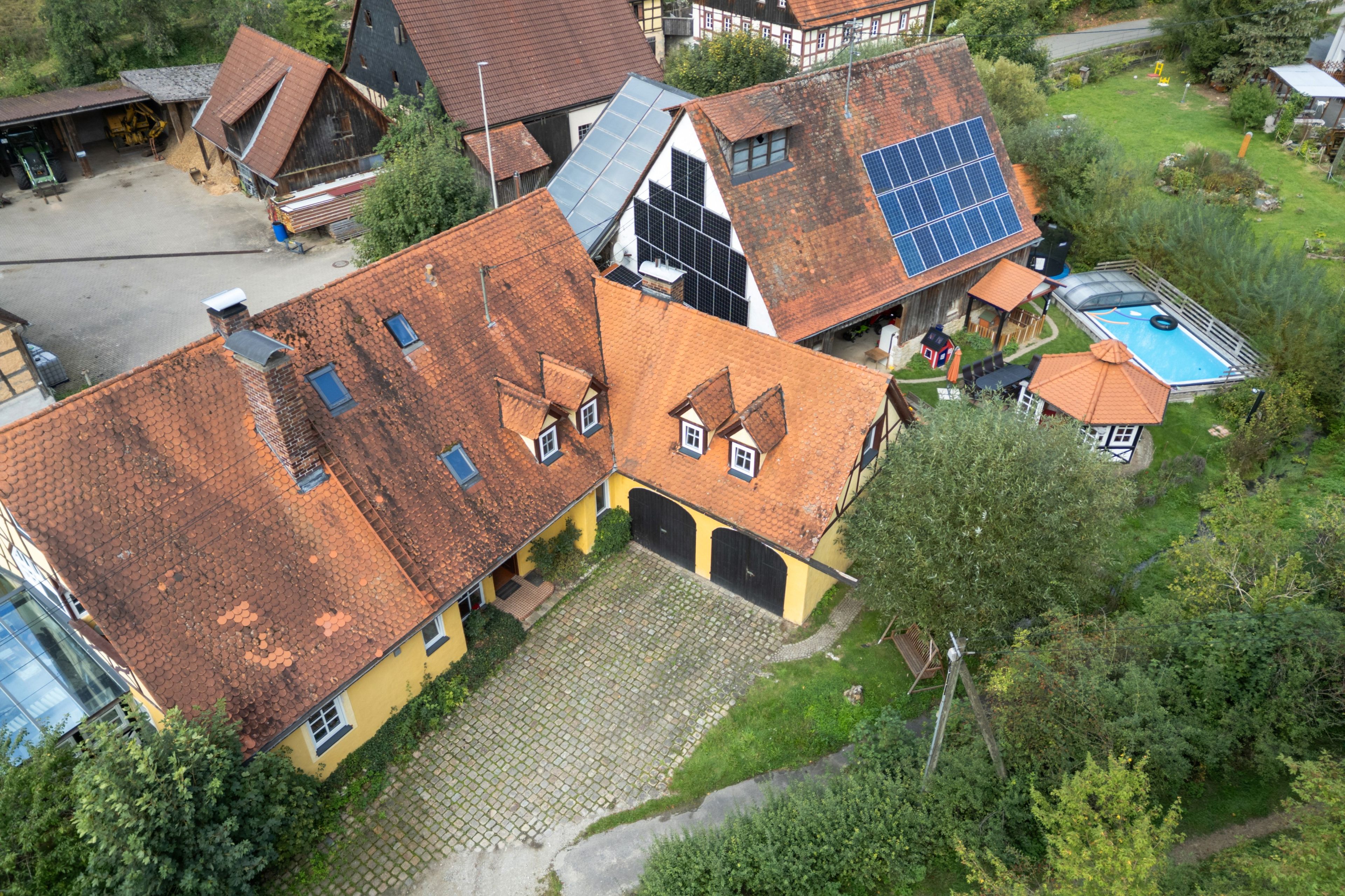 Ein Wohngebiet mit mehreren Häusern, manche mit Solaranlagen, einem Schwimmbad und einer gepflasterten Auffahrt.
