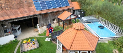 Et hus med garage, swimmingpool og et lille legeområde.