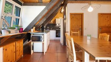 A kitchen with a wooden ceiling, a dining table, and a view of the outside.