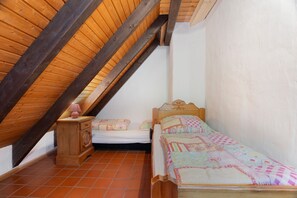 Un dormitorio acogedor en el ático, con techo inclinado, cama de madera, mesita de noche y lámpara.