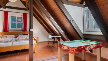 Een gezellige zolderkamer met een bed, een klein tafeltje en een pooltafel.