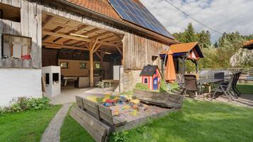 Ein rustikaler Schuppen mit überdachtem Außenbereich, Solaranlagen und einem Spielbereich mit Spielzeugfahrzeugen.