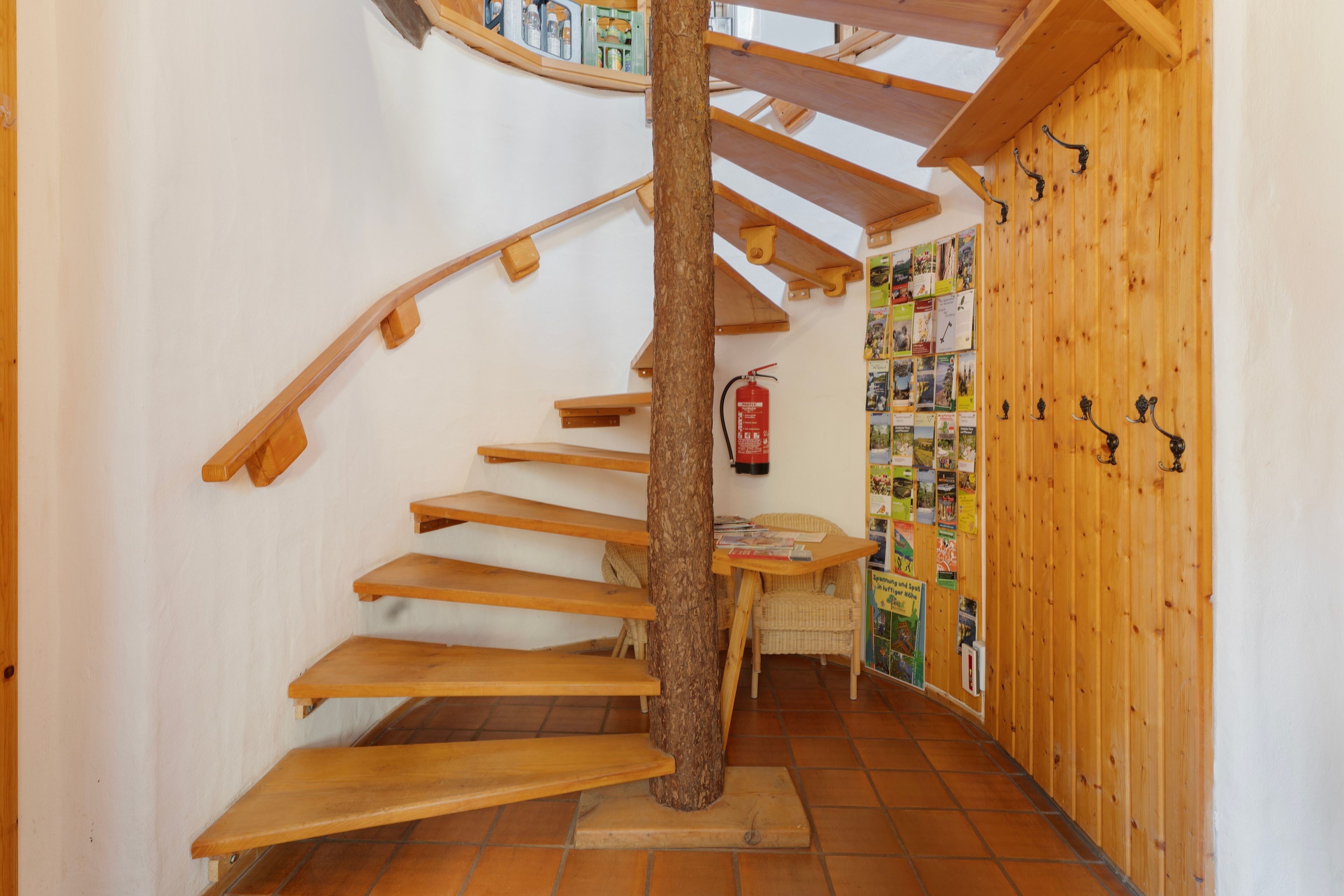 A spiral wooden staircase with a fire extinguisher on the wall.