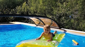 Niño en una piscina con flotador inflable transparente.
