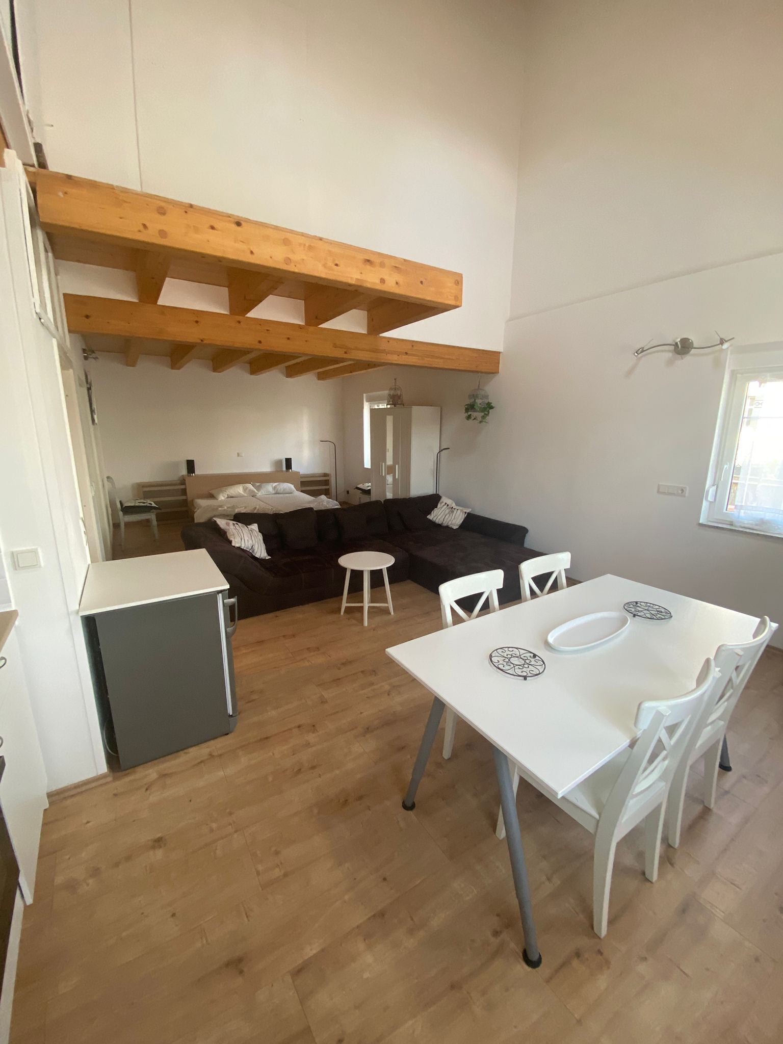 A compact living space with a kitchenette, a dining area, and a seating area with a sofa and chairs.
