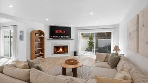 A modern living room with a fireplace, a Netflix TV, and a large sofa. - Outrigger Beach Retreat w/ Private Path & Firepit (Oxnard)