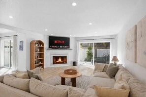 A modern living room with a fireplace, a Netflix TV, and a large sofa. - Outrigger Beach Retreat w/ Private Path & Firepit (Oxnard)