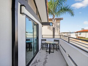 A balcony with a glass door, a table with chairs, and a palm tree.