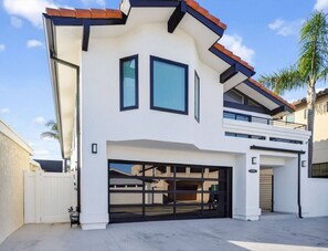 A modern two-story house with a garage, a balcony, and a clear sky.