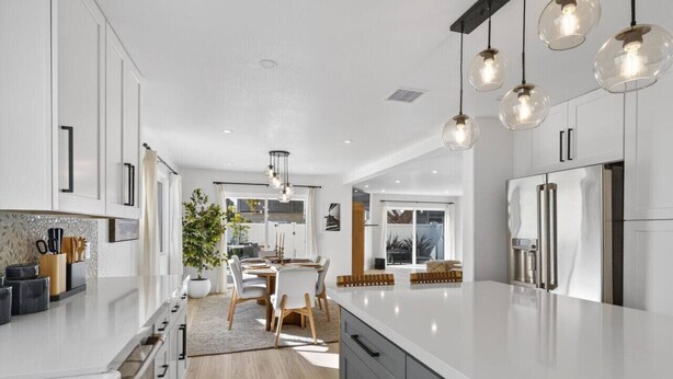 A modern kitchen with white cabinetry, a large island, and pendant lighting. - Outrigger Beach Retreat w/ Private Path & Firepit (Oxnard)