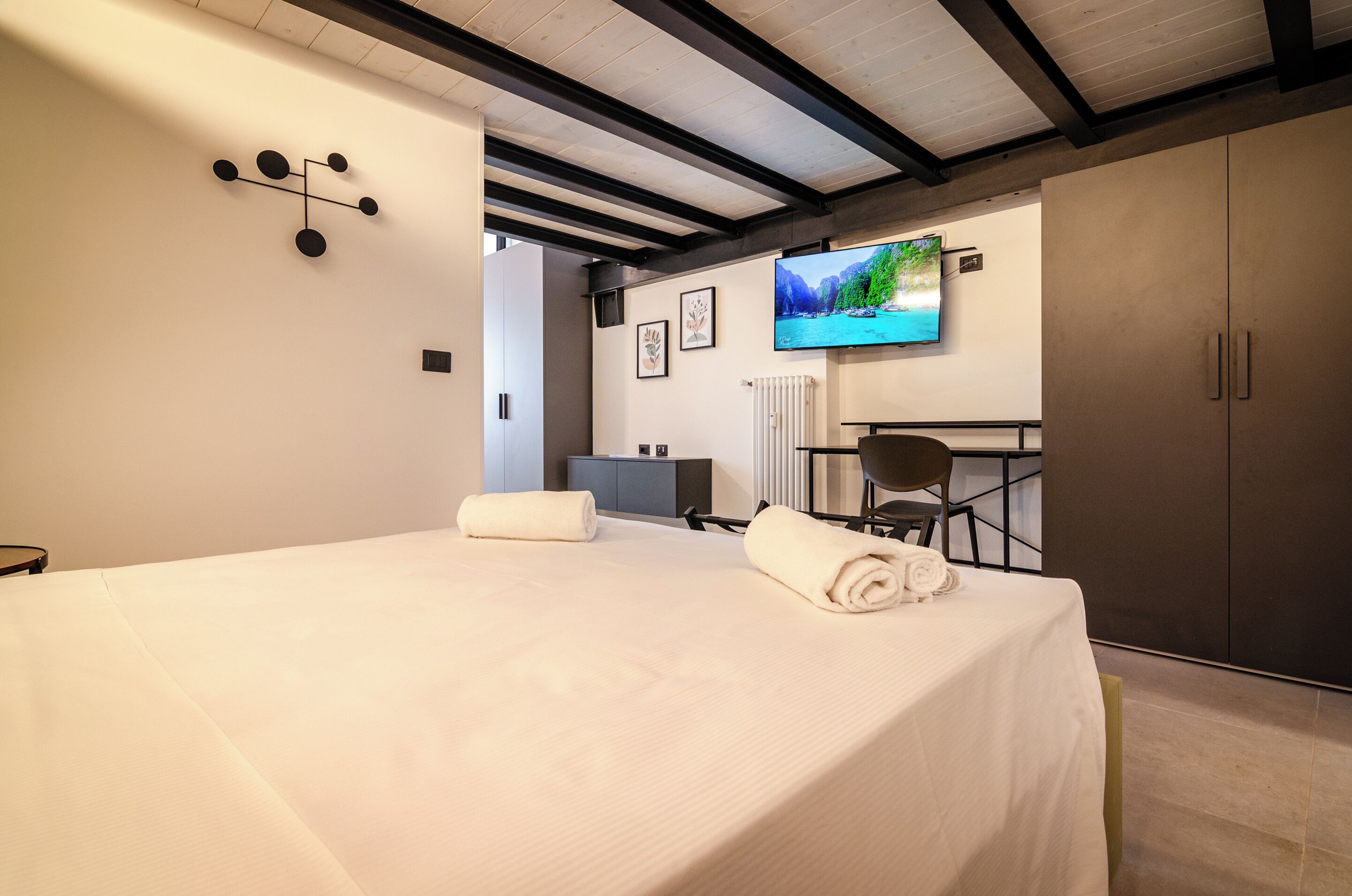 A hotel room with a bed, a TV, a desk, and a wardrobe.