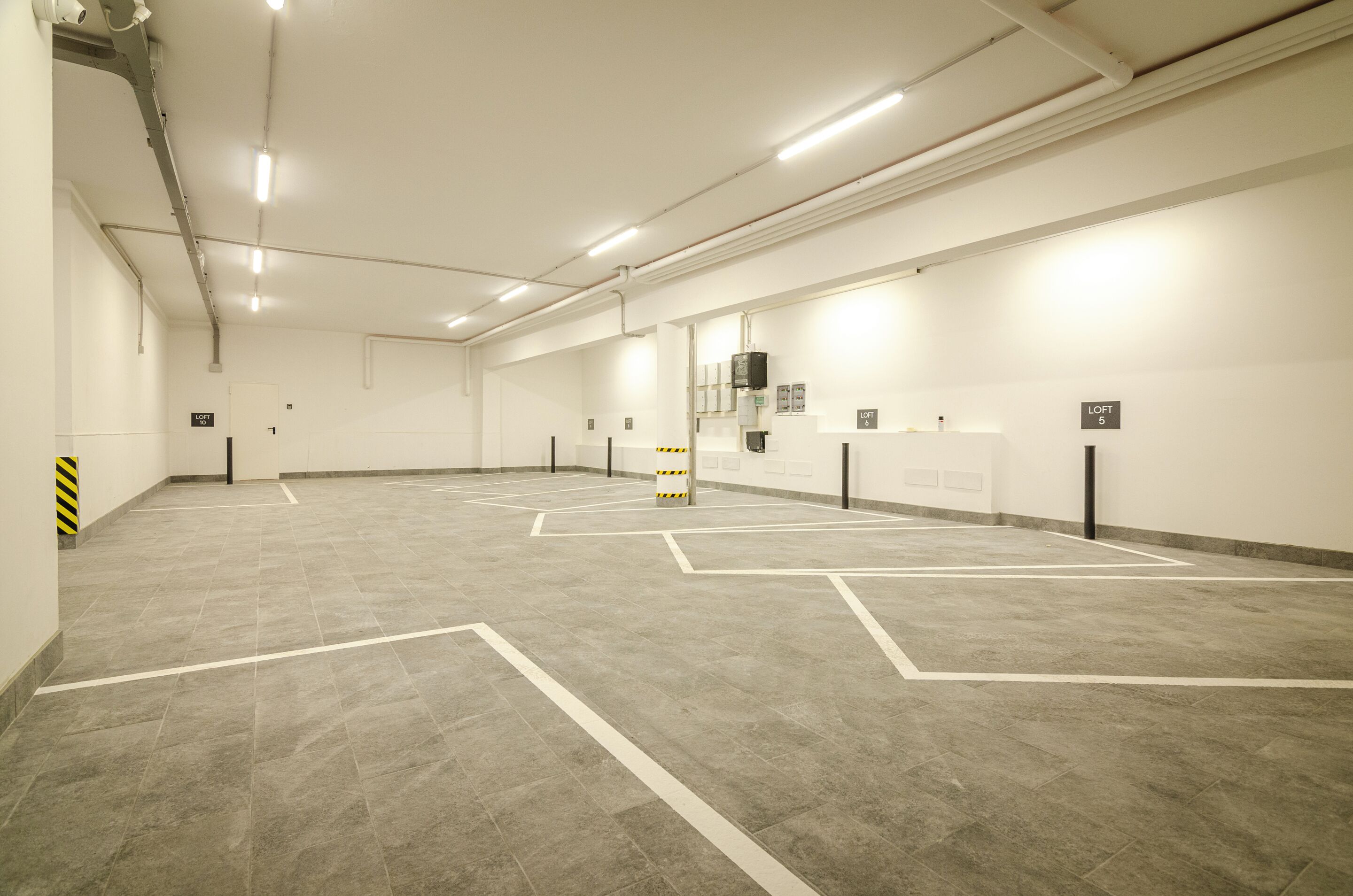 A clean, well-lit parking garage with marked parking spaces and a fire extinguisher.