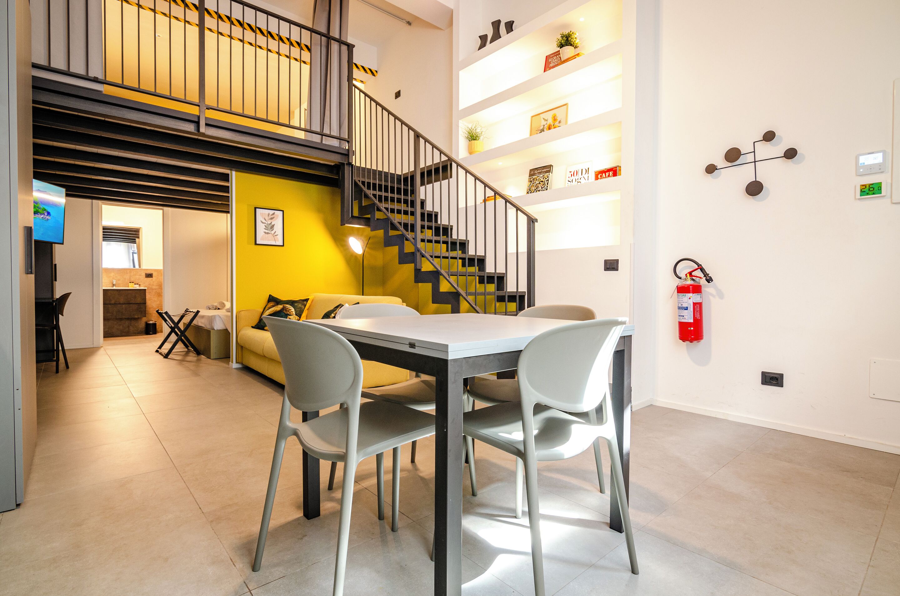 A modern interior with a dining area, a staircase, and a fire extinguisher on the wall.
