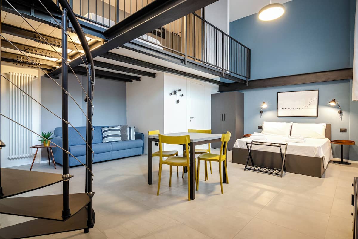 A modern interior with a dining area, a sofa, a bed, and a staircase.